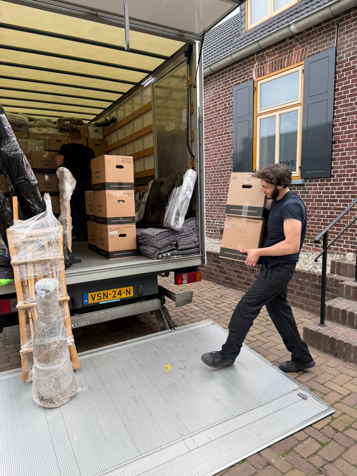 Verhuizer draagt dozen de laadklep op