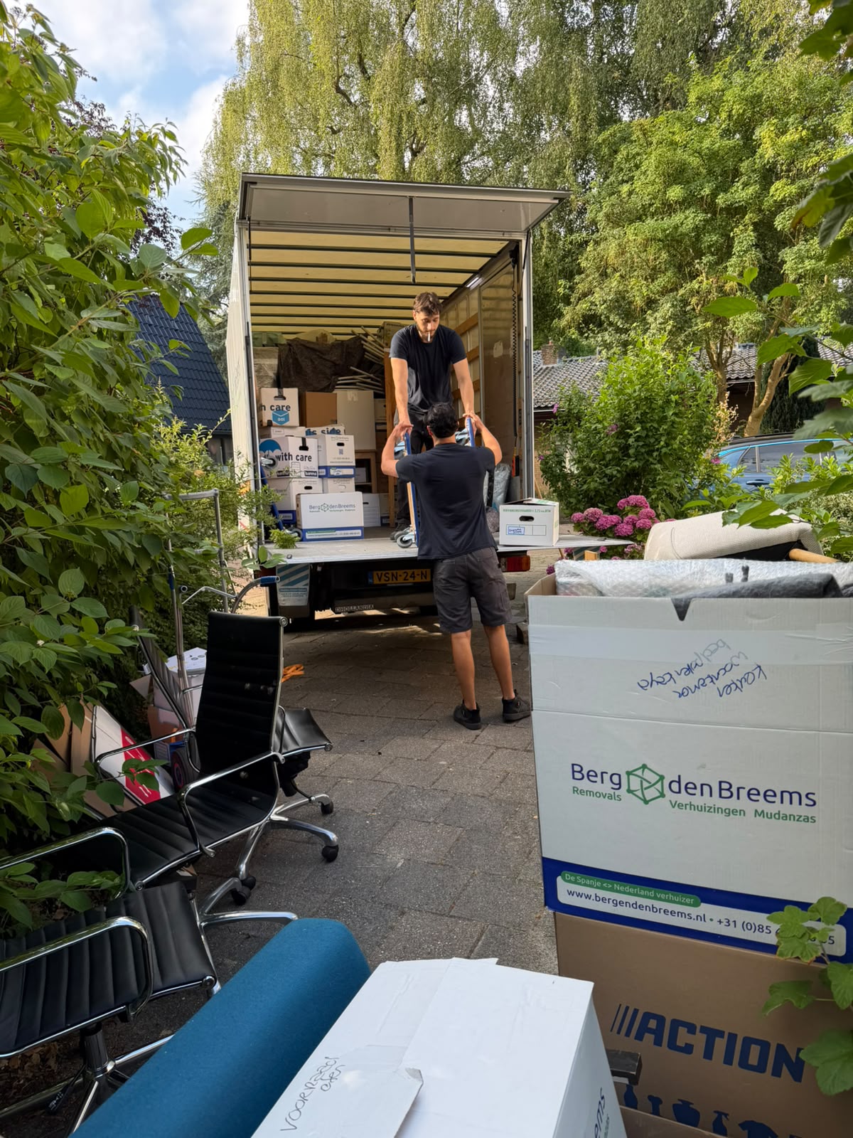 Verhuizers laden dozen van Berg en den Breems in de wagen