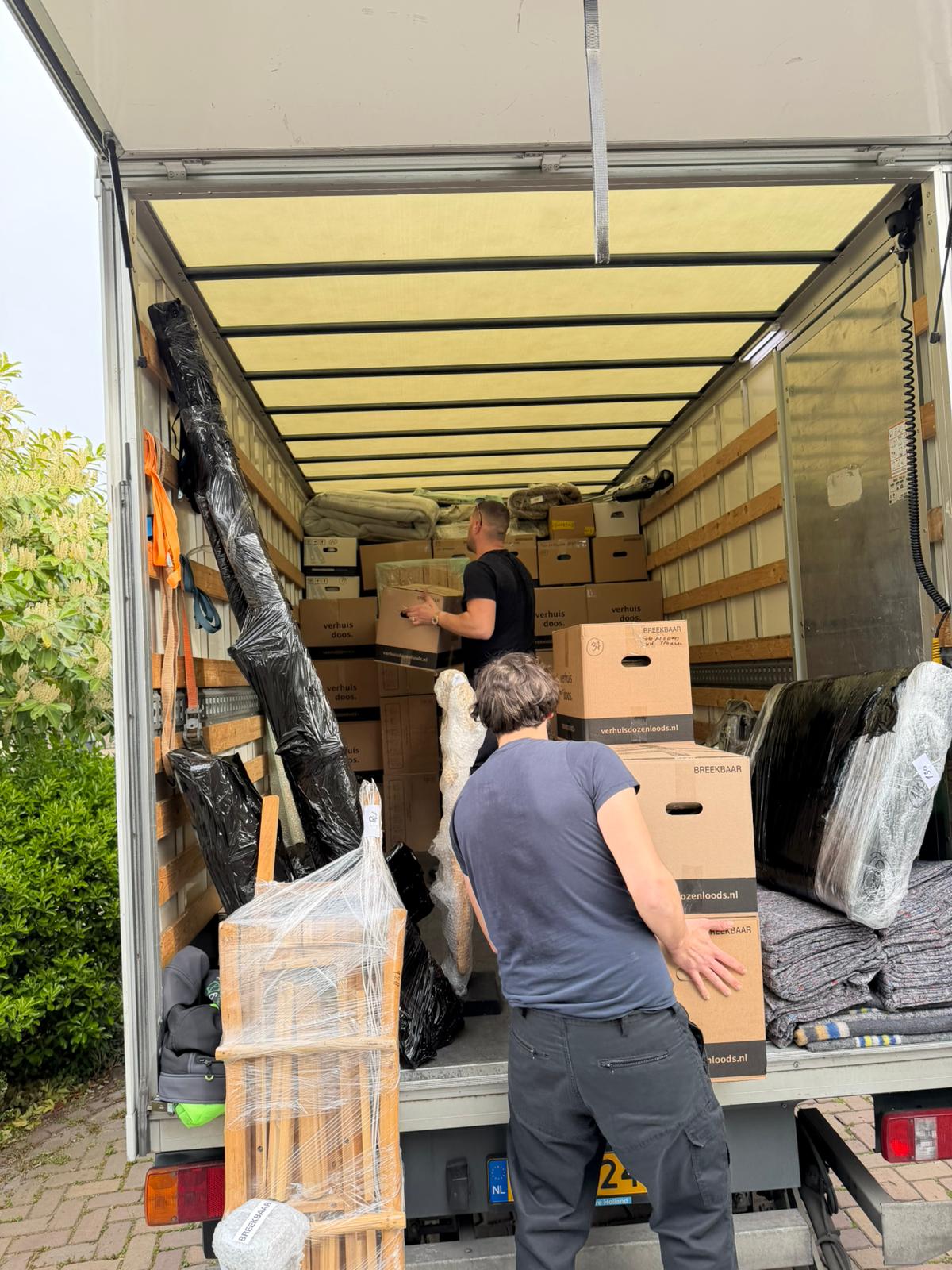 Verhuizers laden inboedel in de wagen
